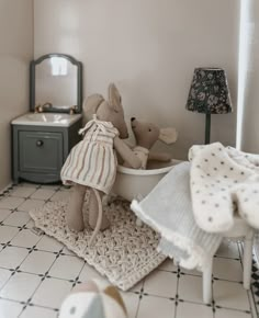 two teddy bears sitting in a bathtub with towels on the floor next to it