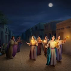 three women dressed in colorful robes and holding candles are walking down the street at night