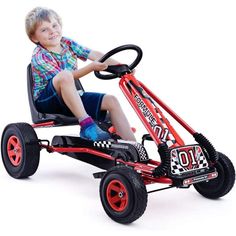 a young boy is sitting in a race car pedaled to the side and smiling at the camera