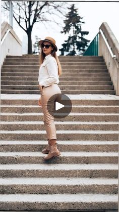 a woman standing on some steps wearing a hat and sunglasses