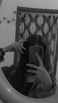 a woman taking a selfie in front of a mirror with her hand on her hair