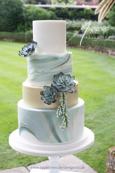 a three tiered wedding cake with succulents on it