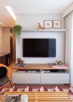 a living room with a large television mounted on the wall above it's entertainment center