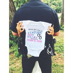 a police officer is holding a baby in his back while wearing a t - shirt