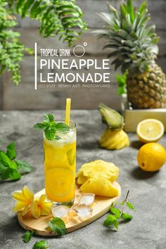 tropical drink pineapple lemonade on a cutting board surrounded by fresh fruit and greenery