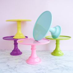 three different colored pedestals on a marble counter top with a mirror in the middle