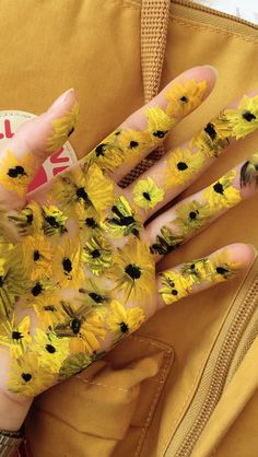 a person's hand with yellow and black flowers painted on it