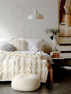 four candles are lit on the wall above a bed with white blankets and throw pillows