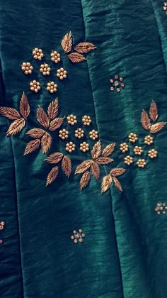 green and gold embroidered fabric with golden flowers on it's side, sitting on a table