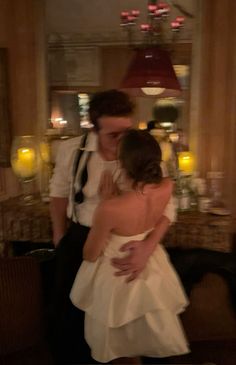 a bride and groom kissing in front of a table with candles on it at their wedding reception