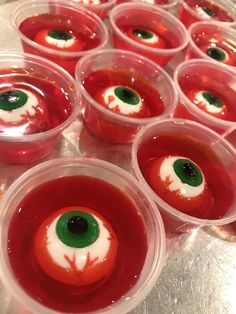 several plastic cups filled with red liquid and green eyeballs