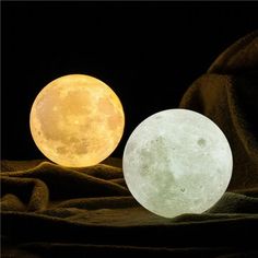 two moon lamps sitting on top of a cloth covered tablecloth in front of a black background