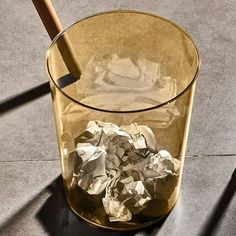 a glass filled with crumpled paper and a wooden stick sticking out of it's side