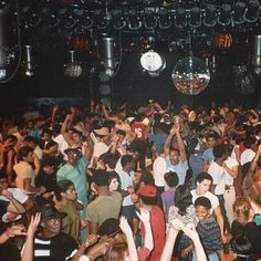 a large group of people are dancing at a club or party with their arms in the air