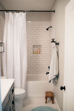 a white bathroom with black and white accessories on the shower curtain, rug, and bathtub