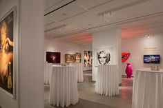 a room filled with tables covered in white tablecloths and pictures on the walls