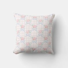 a pink and blue floral pillow on a white wall with a checkered pattern in the background