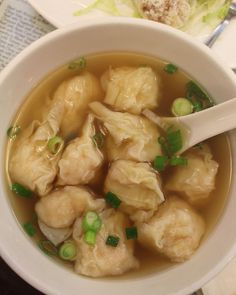 a white bowl filled with dumplings and green onions