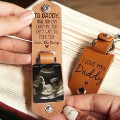 a person holding a keychain with an image of a baby on it and the words i love you daddy