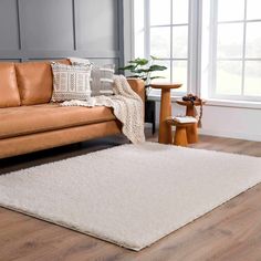 a living room with a brown couch and white rug