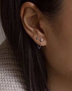 a close up of a person wearing a pair of ear piercings with gold posts