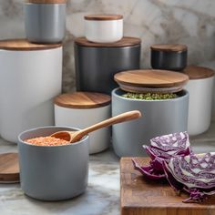 various bowls and wooden spoons with food in them on a counter top next to other containers