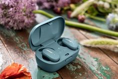 a pair of blue earbuds sitting on top of a wooden table next to flowers