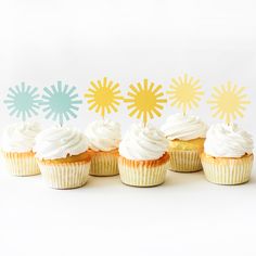 six cupcakes with white frosting and sunburst decorations on each one