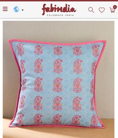 a blue and pink pillow with an intricately designed design on the front, sitting on top of a wooden table