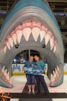 two women pose in front of a fake shark's mouth at an ice rink