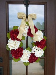 a wreath with red and white flowers is hanging on the front door