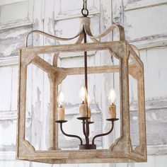 a chandelier hanging from the ceiling with three candles in front of an old door