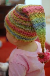 a small child wearing a knitted hat with a flower in it's ear