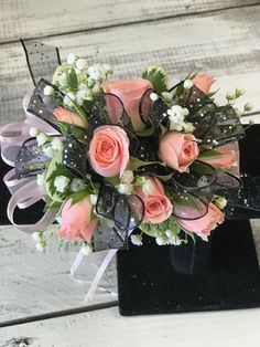 a bouquet of pink roses and baby's breath on top of a black box