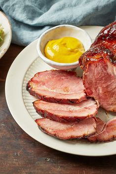 sliced ham on a white plate with mustard and ketchup next to the meat