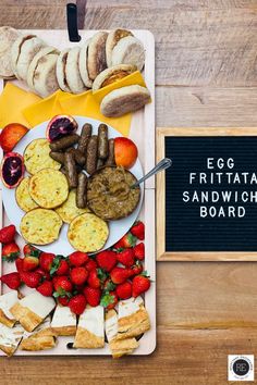 an egg, fruit and sandwich board is displayed on a wooden table with a sign