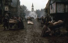 a group of people standing in the middle of a street next to horses and carriages