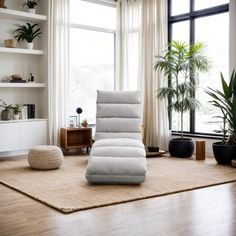 a living room filled with lots of furniture and plants on top of a hard wood floor