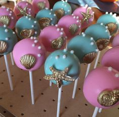 there are many cake pops with different colors and designs on the top one is blue, pink, and gold