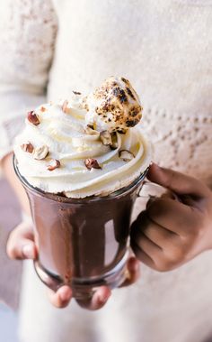 a person holding a cup with whipped cream and chocolate