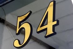 the number 54 is painted on the side of a boat's front end and it appears to be yellow