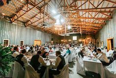 a large group of people sitting at tables in a room filled with white tablecloths