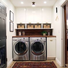 a washer and dryer in a small laundry room with white cabinets, rugs and baskets on the wall