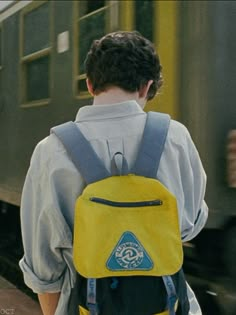 a man with a yellow backpack is waiting for the train