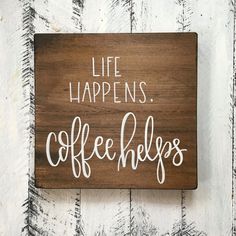 a wooden sign that says life happens coffee helps on the side of a white wall