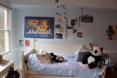 two stuffed animals laying on top of a bed in a room with pictures hanging above it