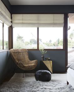 an image of a room with a chair and window in the corner, which has roman shades on it