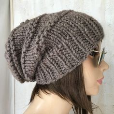 This is a handmade knit slouchy womens hat. The yarn is a wool blend which contains 20% wool-80% acrylic. It's a perfect for winter season. Sizes: One size fits average teen or adult head size of 22" to 23" (50.5 cm to 58 cm). Fiber Content: 80% acrylic, 20% Wool Characteristics: Chunky, very soft, warm and cozy. Care Instructions: Hand wash, dry flat. Every item from srithehat is handmade and knit or crocheted to order, unless otherwise stated in title of the item as "ready to ship". Production time may vary, please check the SHIPPING & POLICIES tab for accurate processing times. If you need an item promptly, please contact us so that we can make arrangements. While every effort is made to accurately represent the true colors of the yarns used in our work, your monitor settings may affect Oversized Hat, Cable Hat, Chunky Knit Hat, Handmade Knitwear, Slouch Beanie, Winter Hats For Women, Slouchy Hat, Pattern Store, Handmade Knitting