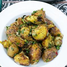 a white bowl filled with cooked potatoes and garnished with parsley on the side