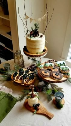 a table topped with cakes and desserts on top of wooden trays next to a window